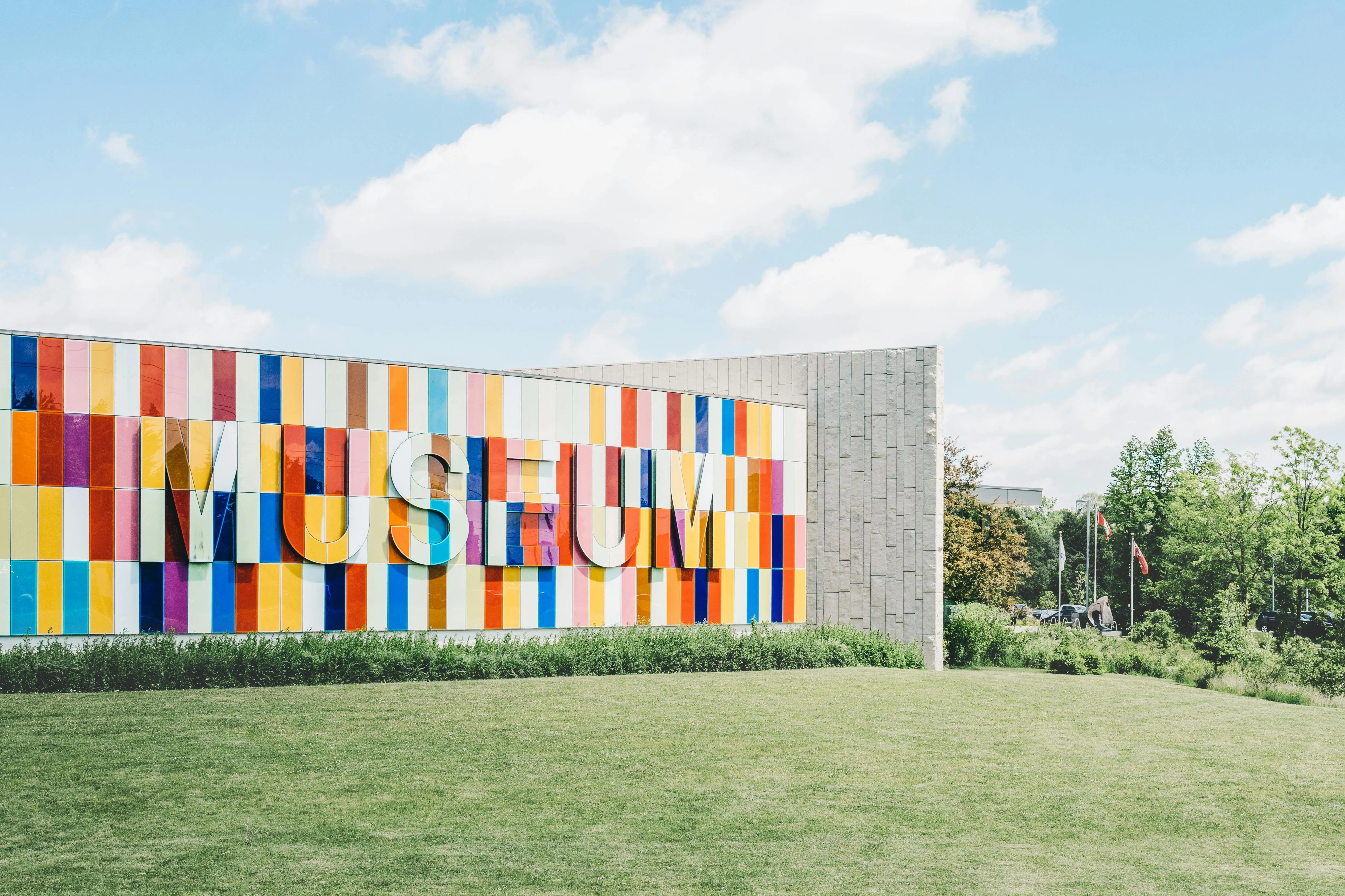 A multi-colored building that says "MUSEUM" on the side, in front of green grass and blue sky.
