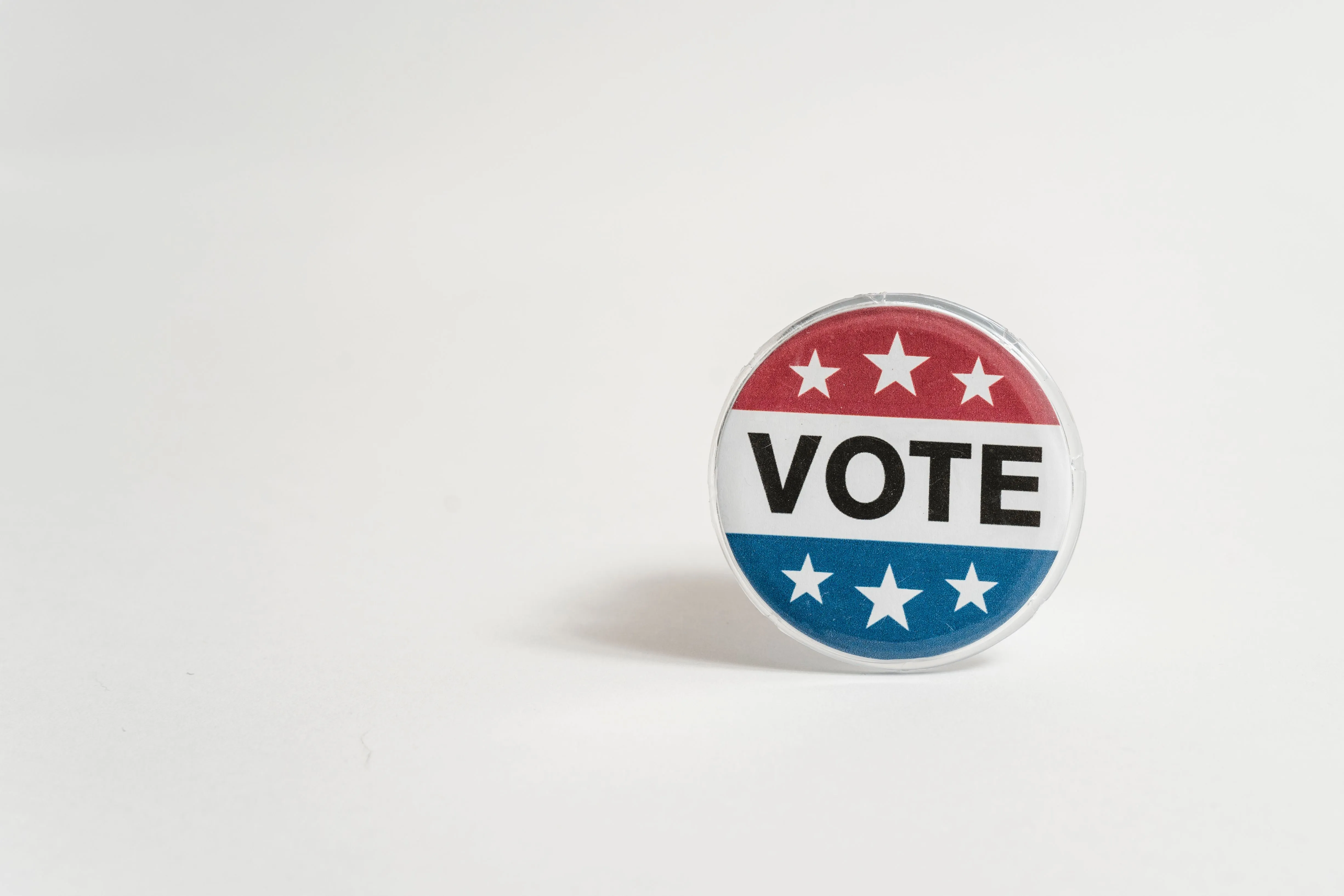 A red, white, and blue vote sticker on a white background.